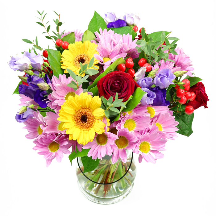 This image shows a lavish mixed-flower bouquet displayed in a clear glass vase, positioned against a plain white background so that every blossom appears crisp and defined, as if ready to be sent out from a Cranford studio for a special occasion. At the core of the arrangement, richly coloured red roses unfurl in velvety layers, giving the bouquet a romantic heart and drawing the eye inward. Sharing the spotlight are bold yellow gerbera daisies with dark brown-orange centres, their broad, daisy-like faces radiating warmth in a way that feels especially uplifting on a grey day in Cranford. Encircling these focal flowers, there is an abundance of soft pink and pale lavender daisies or chrysanthemums, their many slender petals forming a gentle cloud of colour that adds softness and volume. Woven gracefully through this pastel halo are stems of purple and lavender lisianthus, their delicate, bell-shaped blooms lending a touch of cool elegance and bringing subtle height to the design. Small clusters of bright red hypericum berries are tucked between petals and leaves, creating little bursts of glossy texture that echo the deep tones of the roses. A generous selection of greenery-broad, dark green leaves and fine, lighter sprigs-surrounds and supports the flowers, giving the bouquet a lush, rounded silhouette reminiscent of a garden border in full bloom. Through the clear vase, the viewer can see the neatly trimmed stems, carefully arranged in clean water, reflecting the professional care that local Cranford florists put into every arrangement. The gentle, even lighting enhances each colour and contour, suggesting a mood of quiet joy and celebration, as if this bouquet were about to be carried into a birthday lunch near Cranford Park or offered as a thoughtful thank-you to a neighbour.